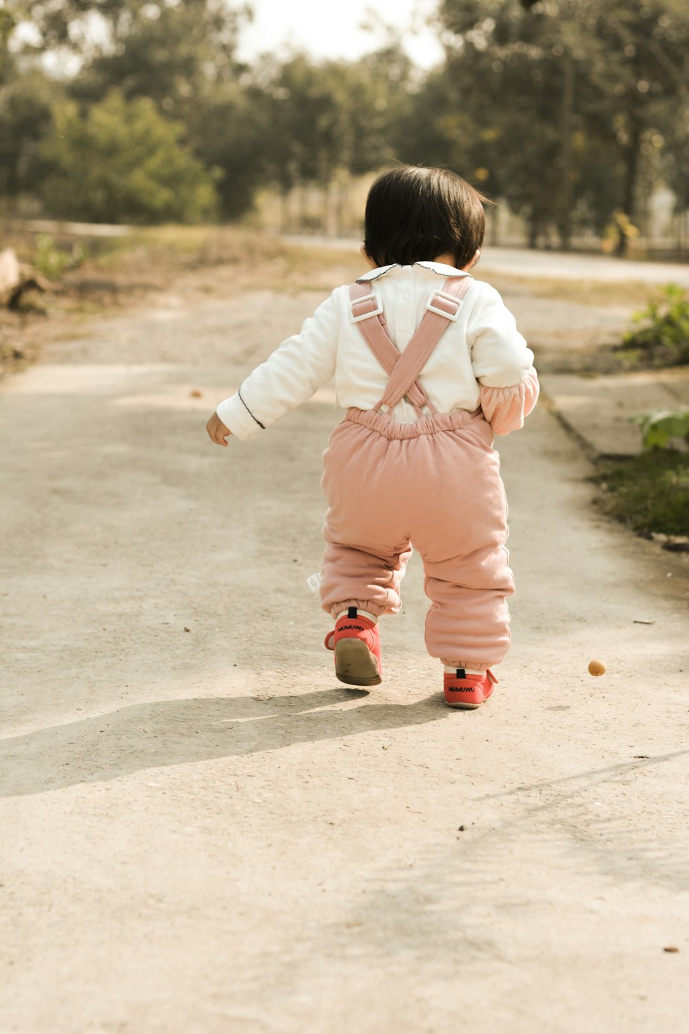 toddler walking on pathway during daytime