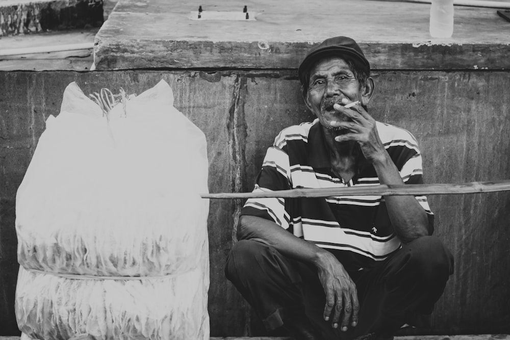 Foto in scala di grigi di un uomo in procinto di fumare