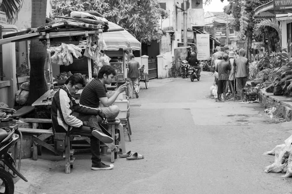 grayscale photo of two men sitting next to each other