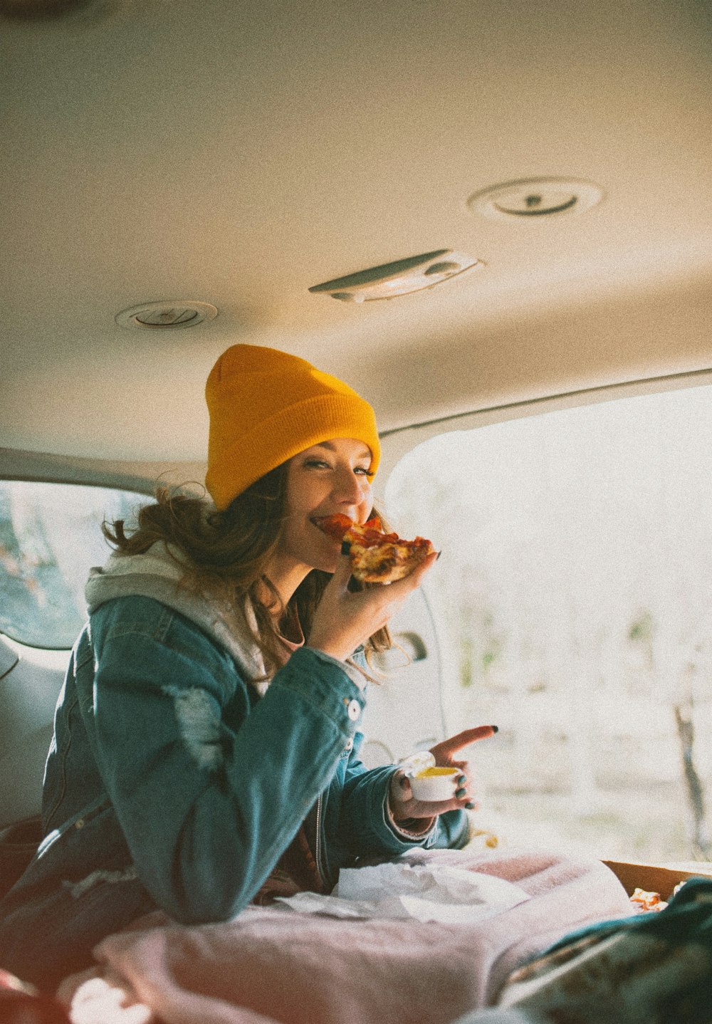 Frau isst Pizza im Fahrzeug