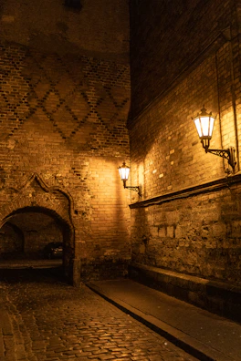 A narrow cobblestone alleyway with vintage street lamps glowing at dusk