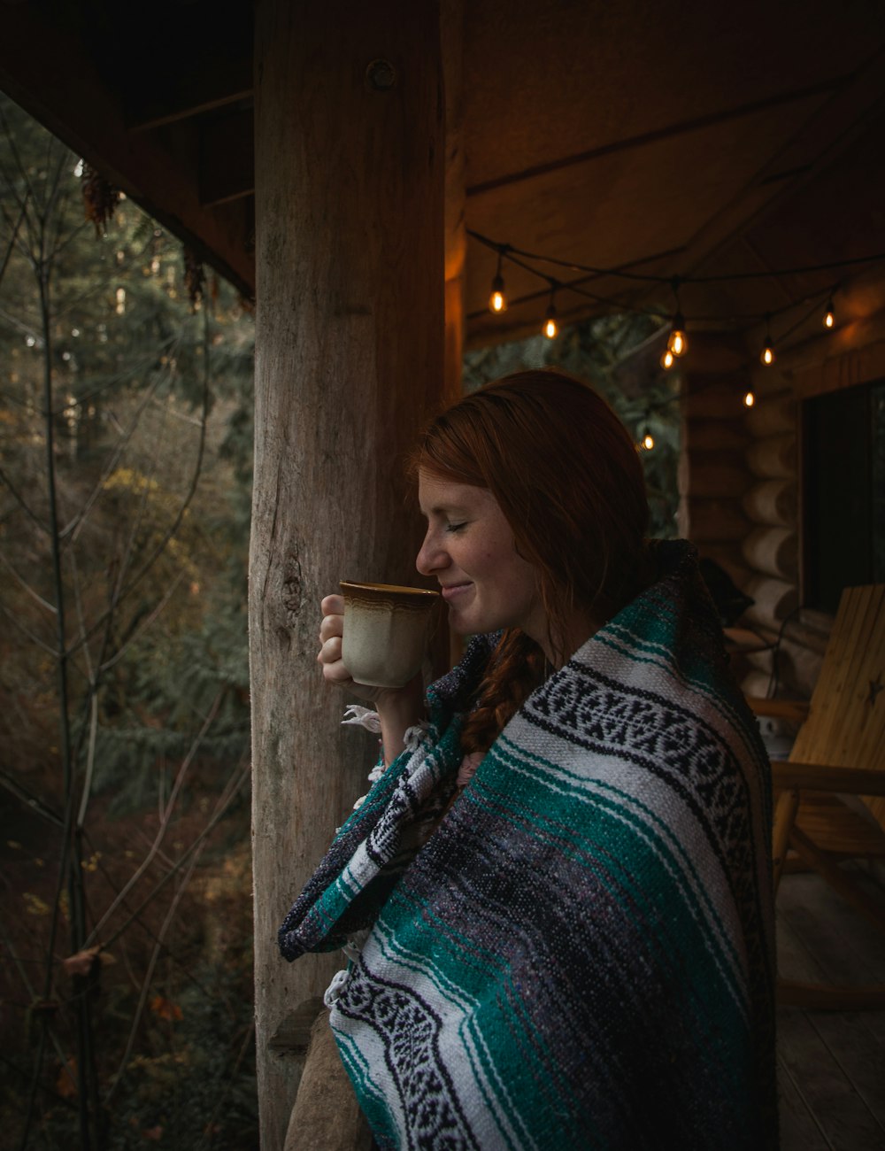 woman covering blanket standing and holding and smelling coffee