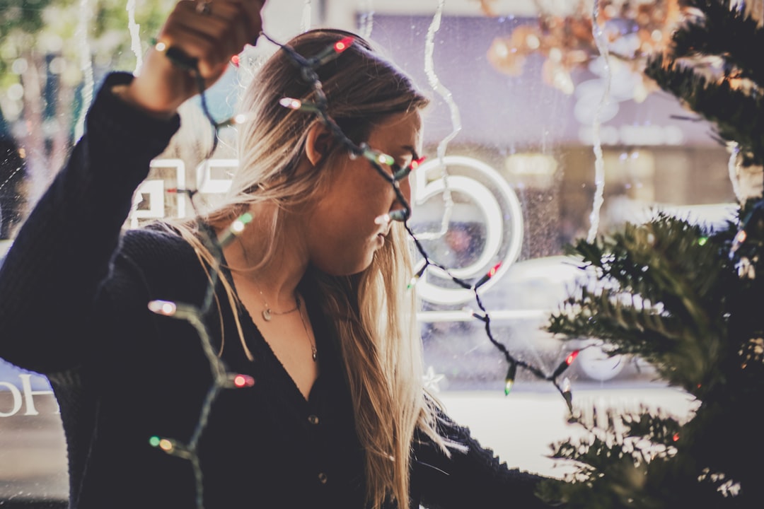 woman putting string light to the christmas tree