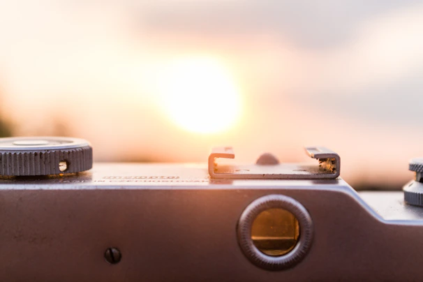 A close-up of a camera operator adjusting the focus ring on a vintage film camera during a sunset shoot.
