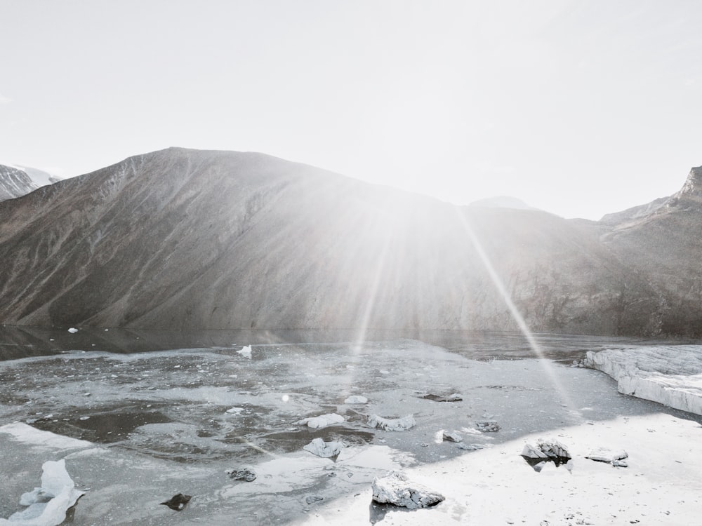Fotografía en escala de grises de una montaña cerca de un cuerpo de agua