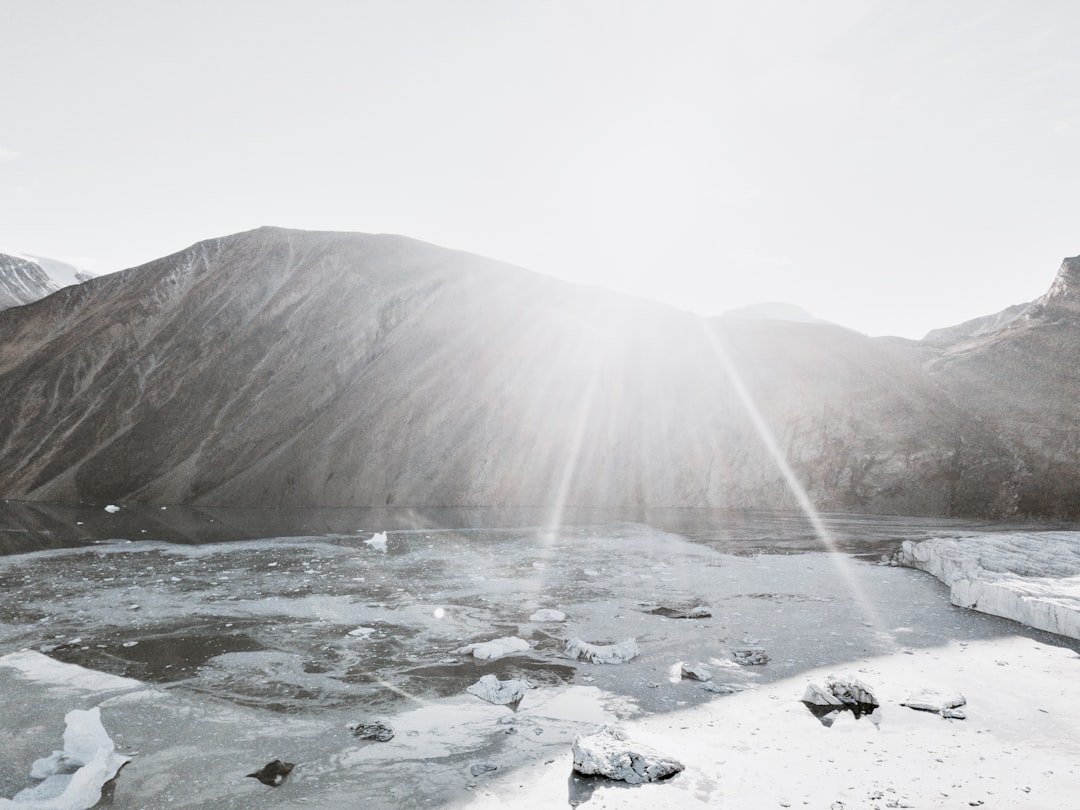 grayscale photography of mountain near body of water