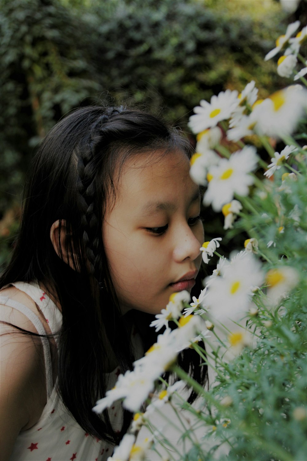 menina cheirando flor branca durante o dia