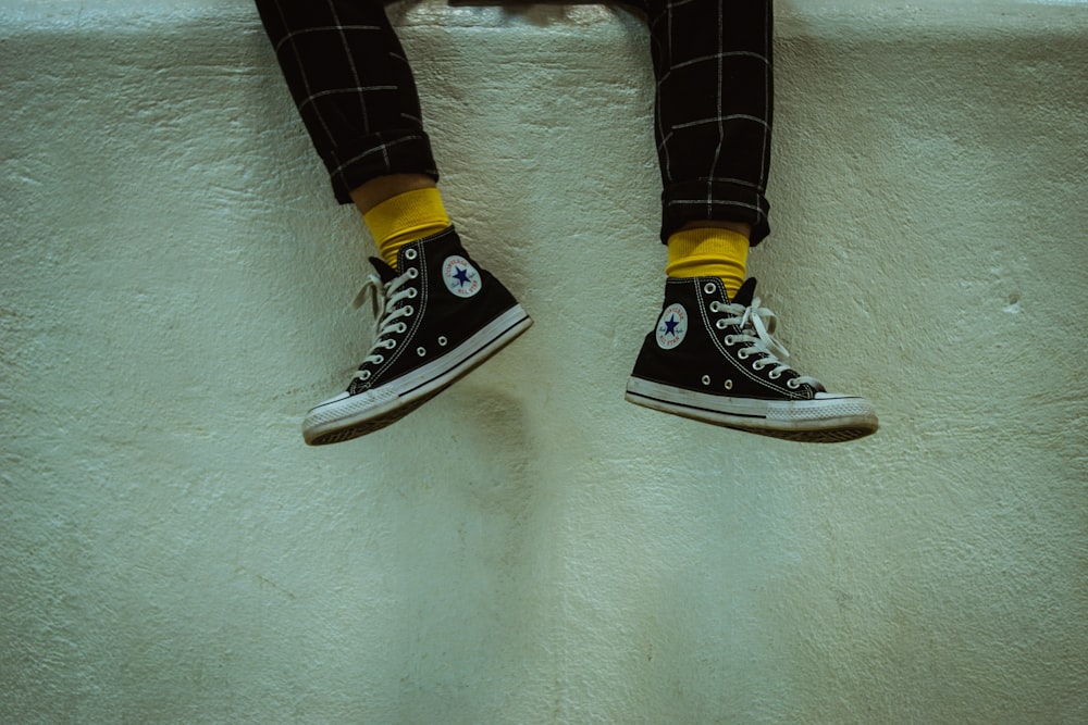 person wearing white-and-black Converse high-top sneakers