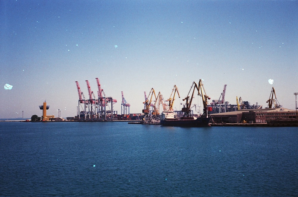 boats and cranes near sea during daytime