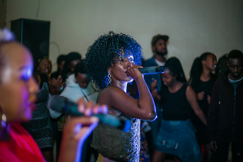 Une chanteuse au micro, au milieu du public, dans une salle éclairée en bleu.