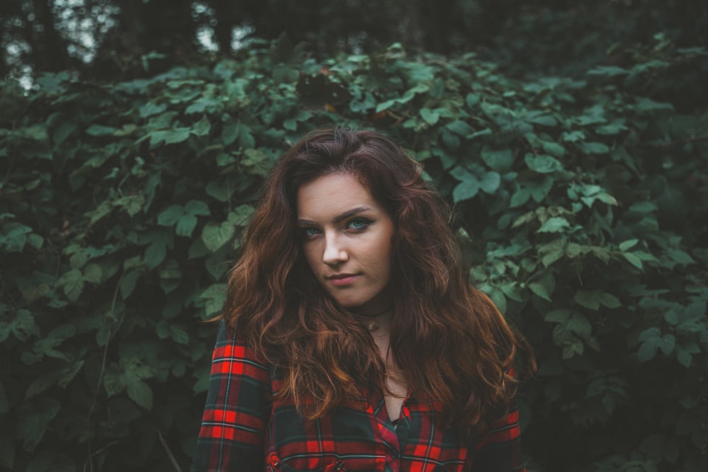 selective focus photography of woman standing beside green leaves