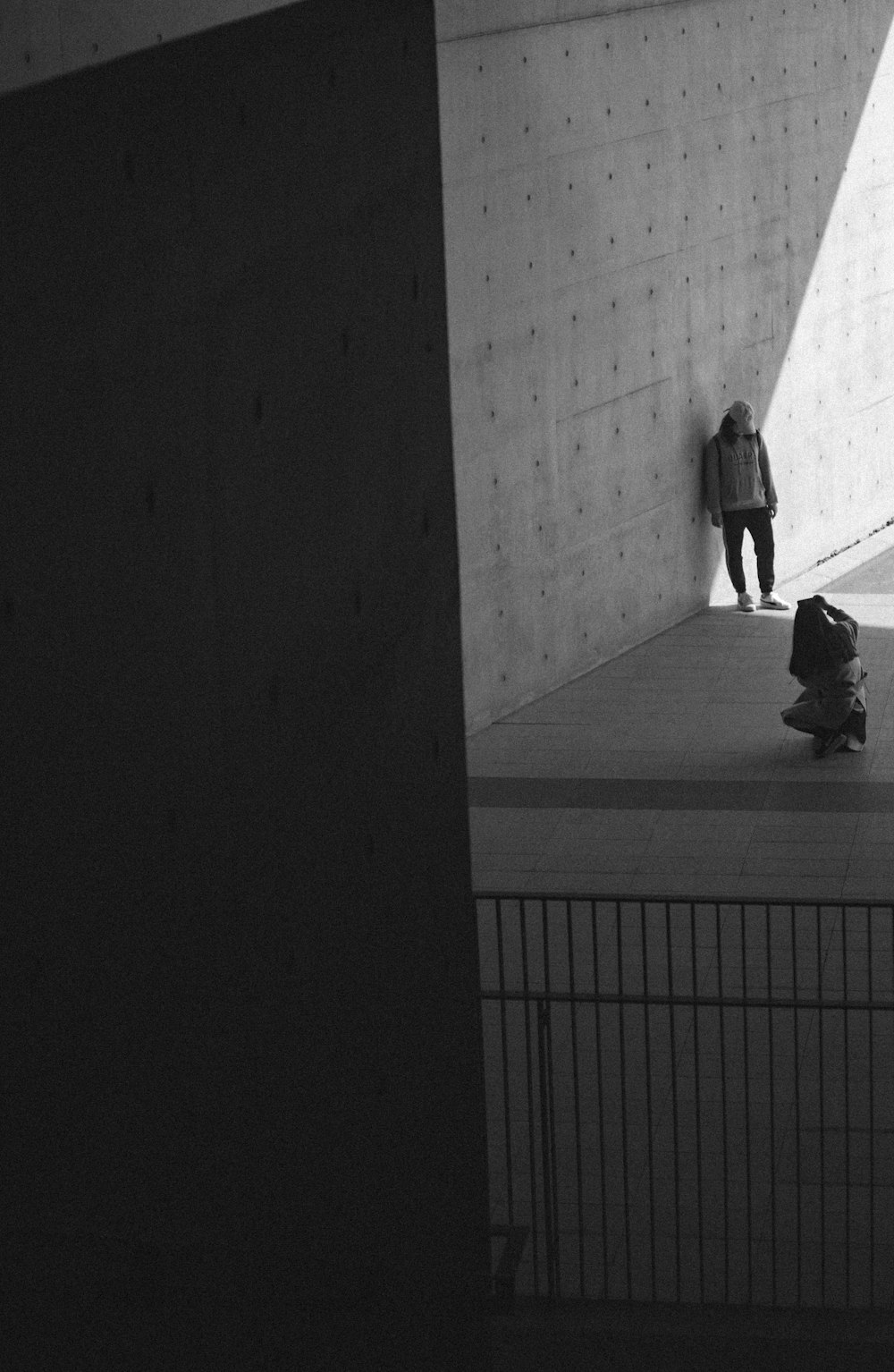 woman taking photo of man leaning on wall