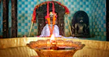 A serene temple corner with flickering oil lamps and fresh flower garlands.