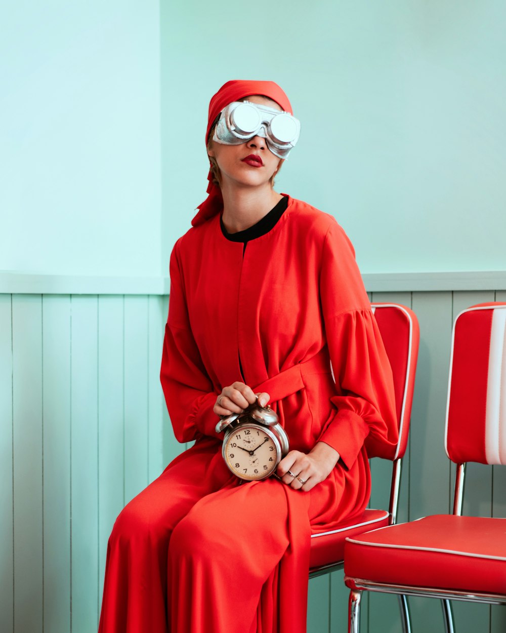 woman sitting while holding analog alarm clock