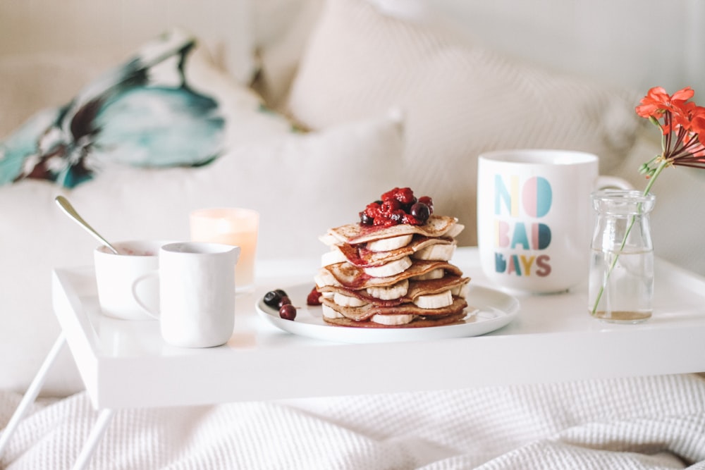 pancake with raspberries on plate beside mugs