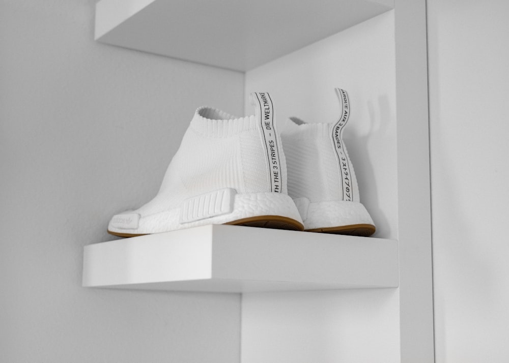 pair of white high-top sneakers on shelf