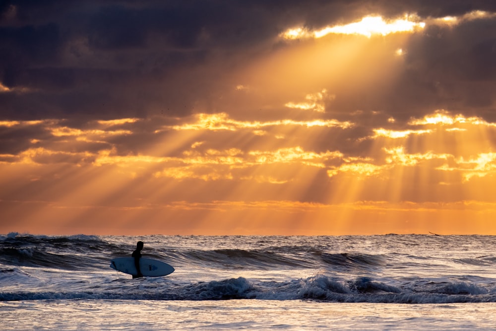 person holding surfboard on body of water