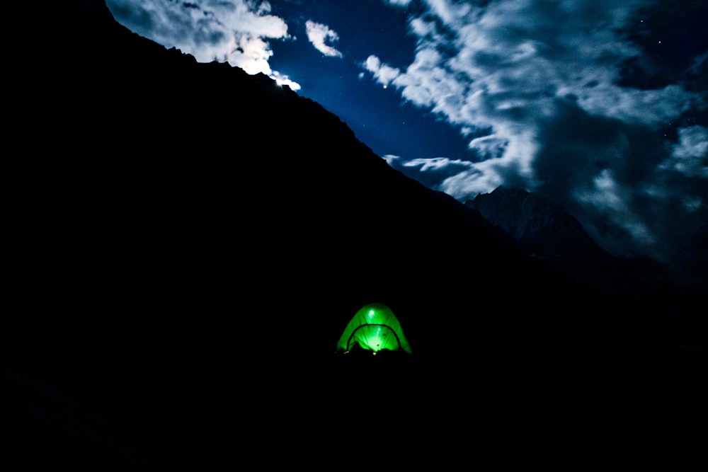 lighted green camping tent under cloudy sky