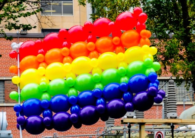 A vibrant balloon arch framing a cheerful birthday party scene outdoors.