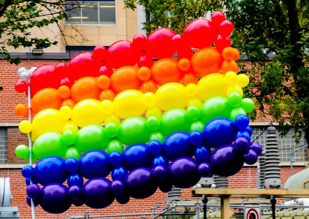 A vibrant balloon arch framing a joyful birthday party scene outdoors.