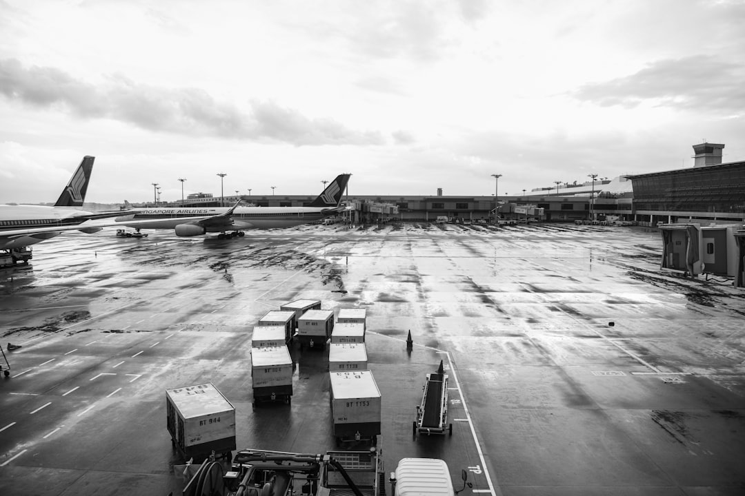 grayscale photography of cargo trailers by airplanes