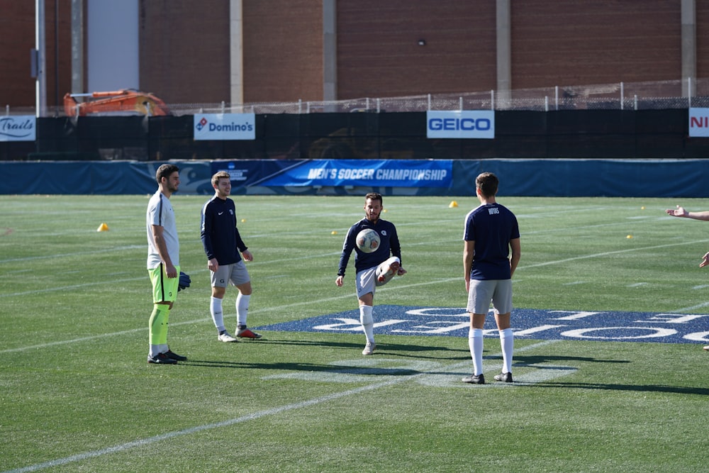 four person playing soccer on field during daytime