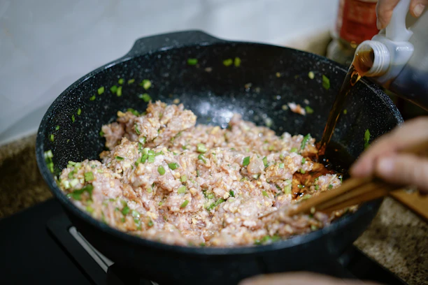 Close-up of a student frying pad thai in a warm, lively kitchen with a chef guiding.