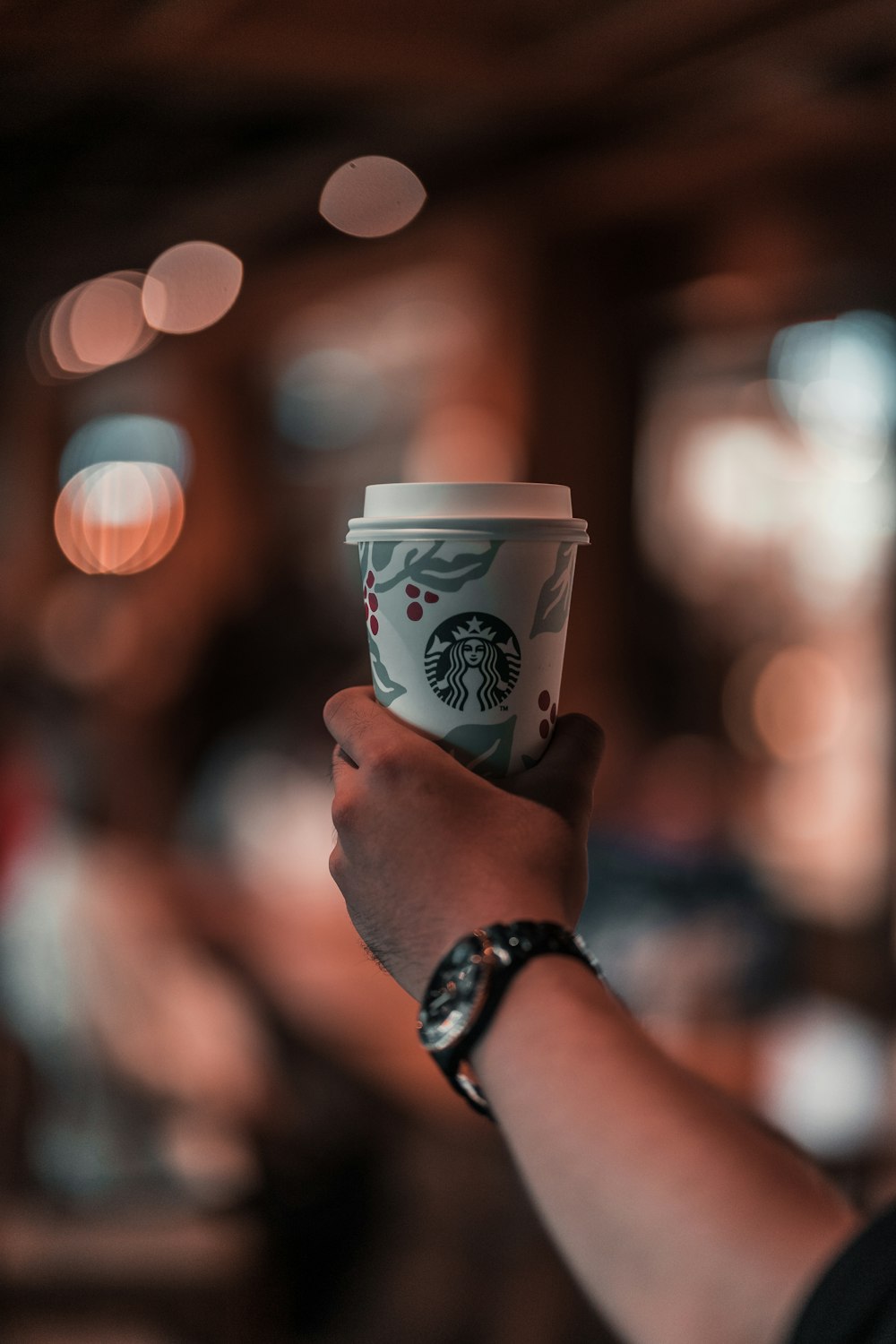 pessoa segurando copo descartável Starbucks branco com tampa