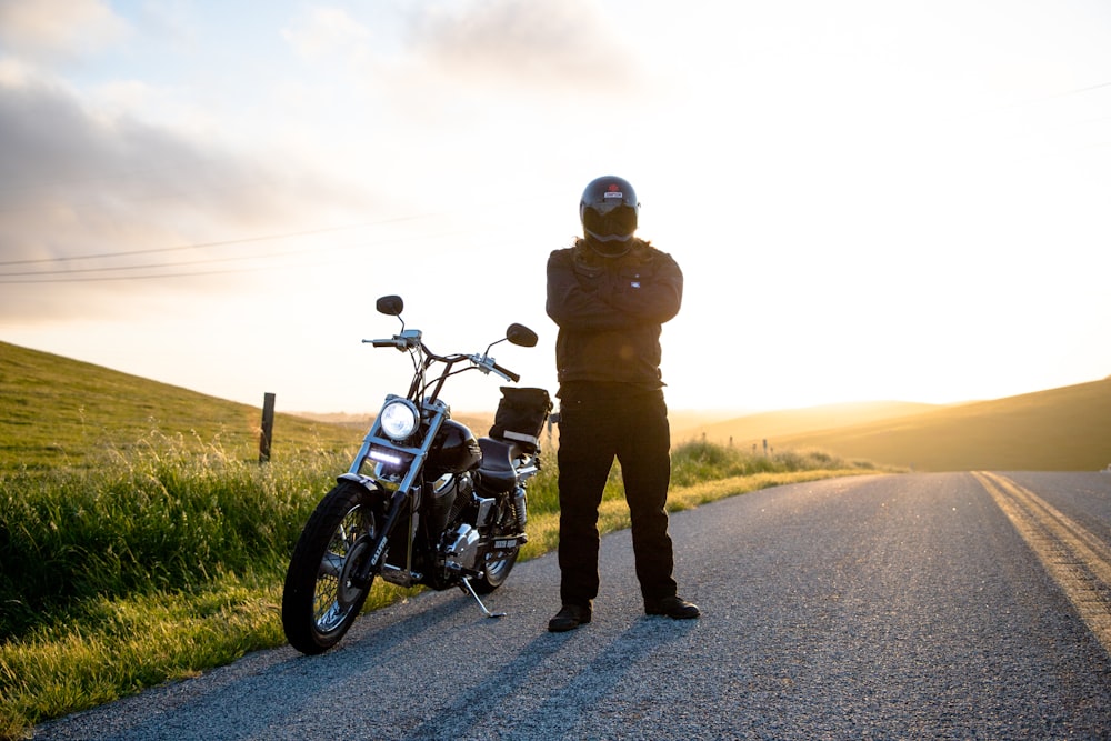 man wearing helmet standing beside motorcycle