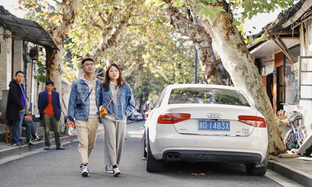 couple waking near white Audi sedan during daytime