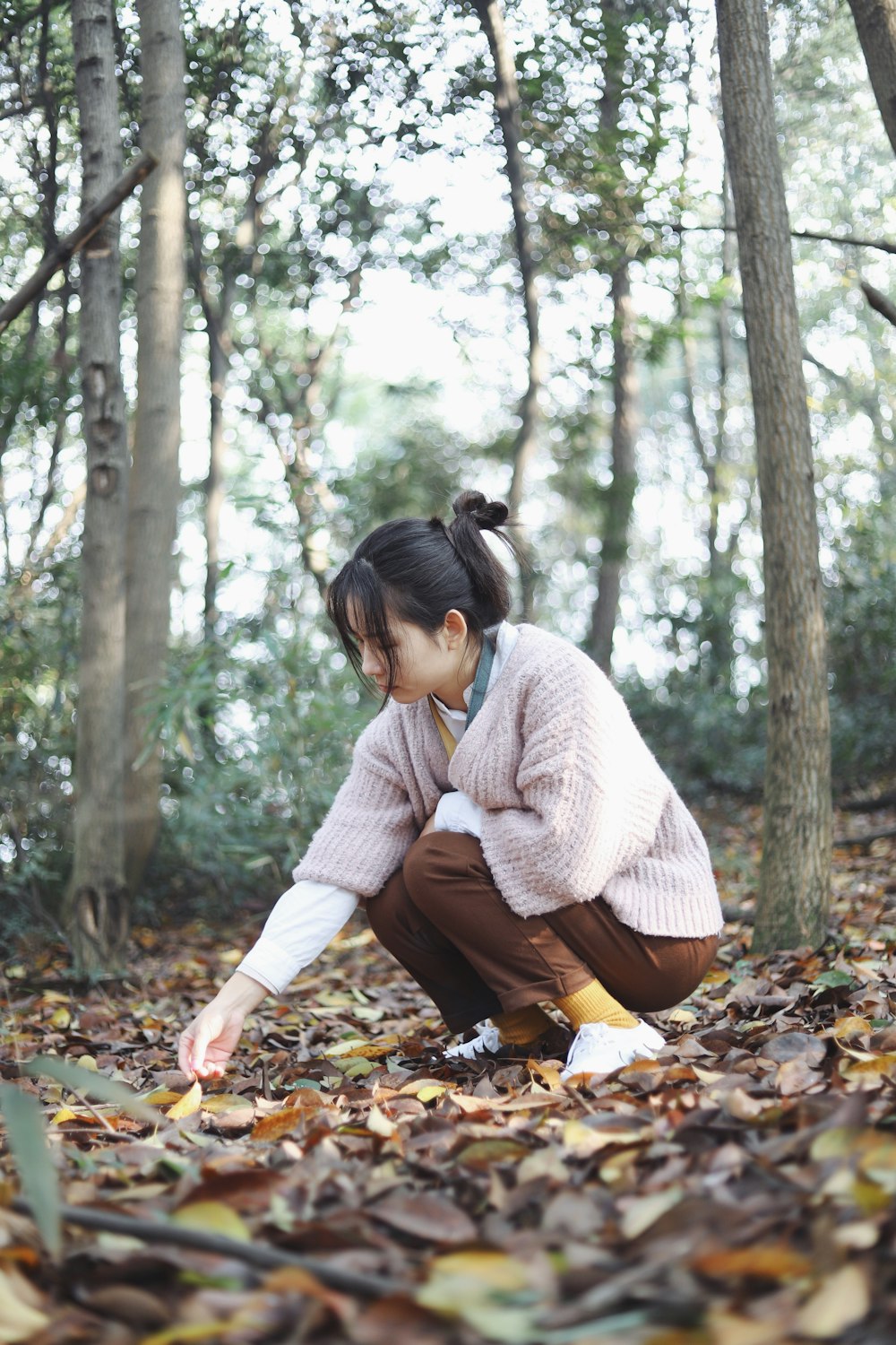 woman picking dried leaves in forest