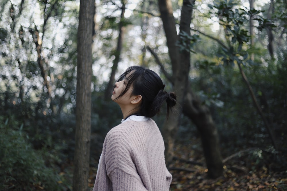 selective focus photography of woman wearing brown cardigan surrounded by trees during daytime