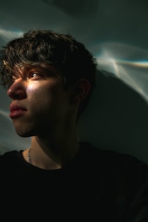 A reflective selfie of a young boy looking thoughtful, shadows playing across his face, symbolizing internal struggles.