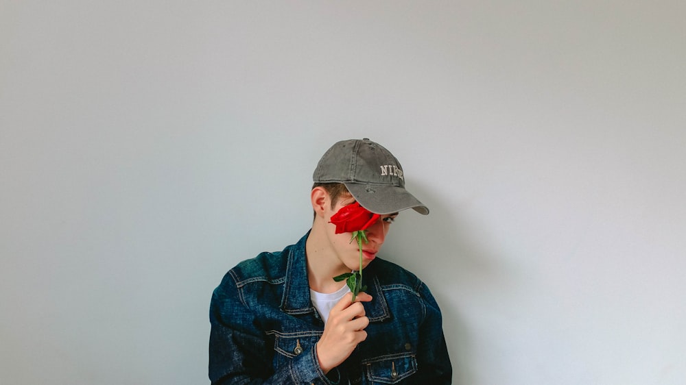 Mann in Jeansjacke mit Rose im Gesicht