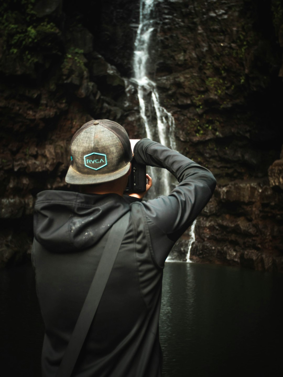 man taking photo of waterfalls