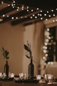 A glowing bottle centerpiece framed by fairy lights and candles for an intimate evening setting.