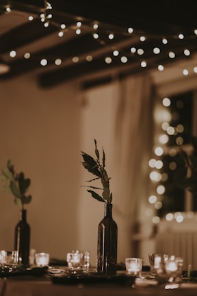 A glowing bottle centerpiece framed by fairy lights and candles for an intimate evening setting.