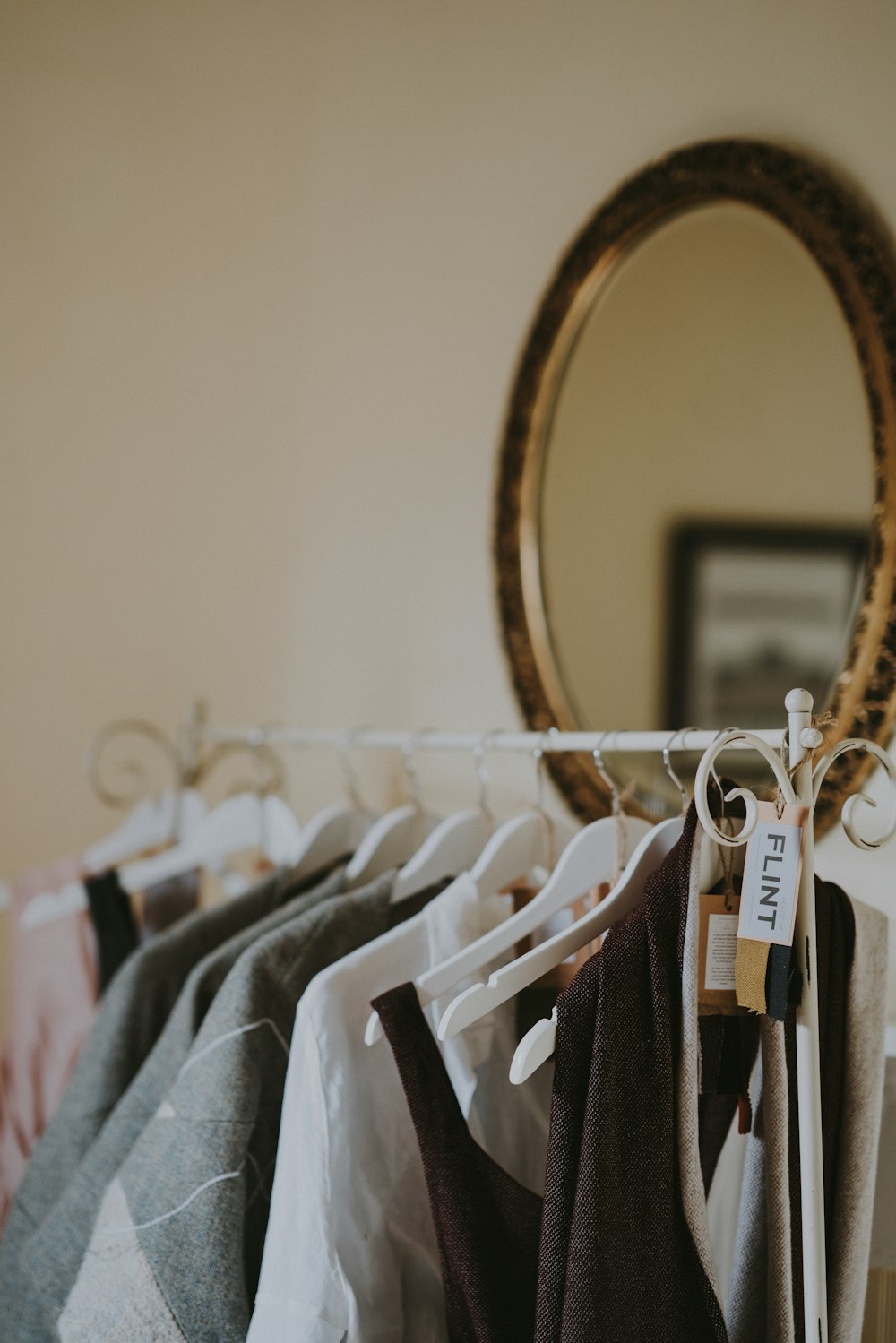 assorted-color top hanged on hangers near wall mirror