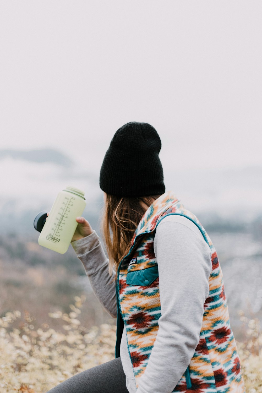 woman holding tumbler near flowers