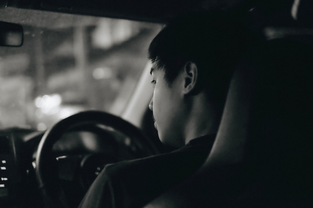 grayscale photography of man driving car