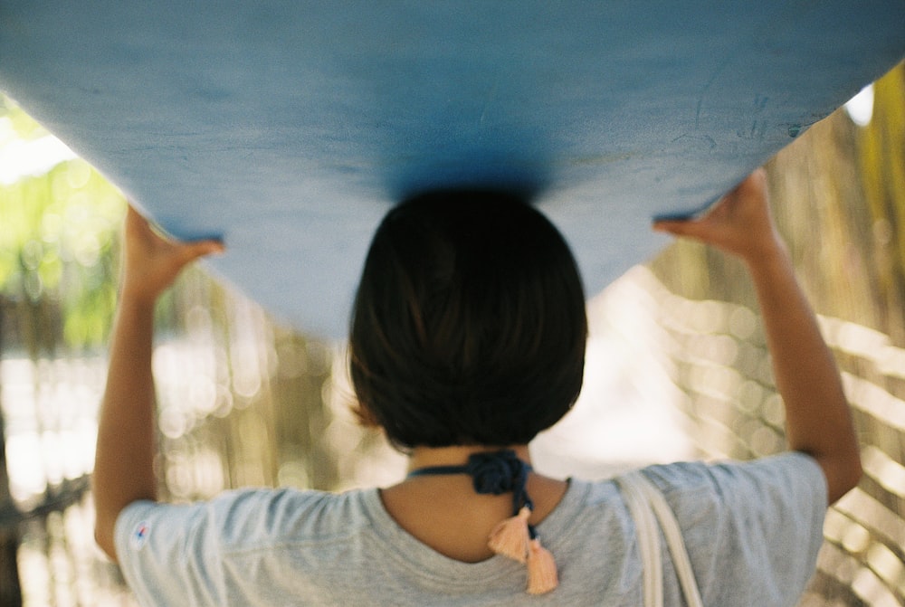 woman carrying blue board on her head