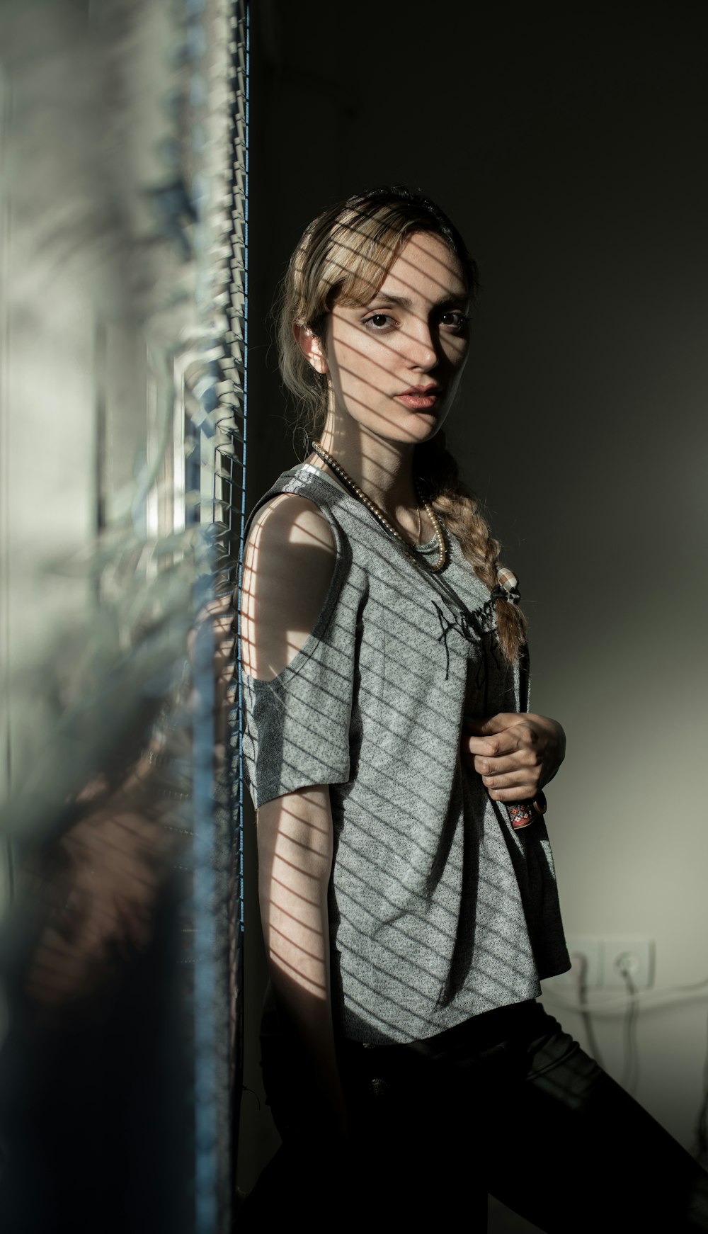 woman in gray off-shoulder top leaning on wall