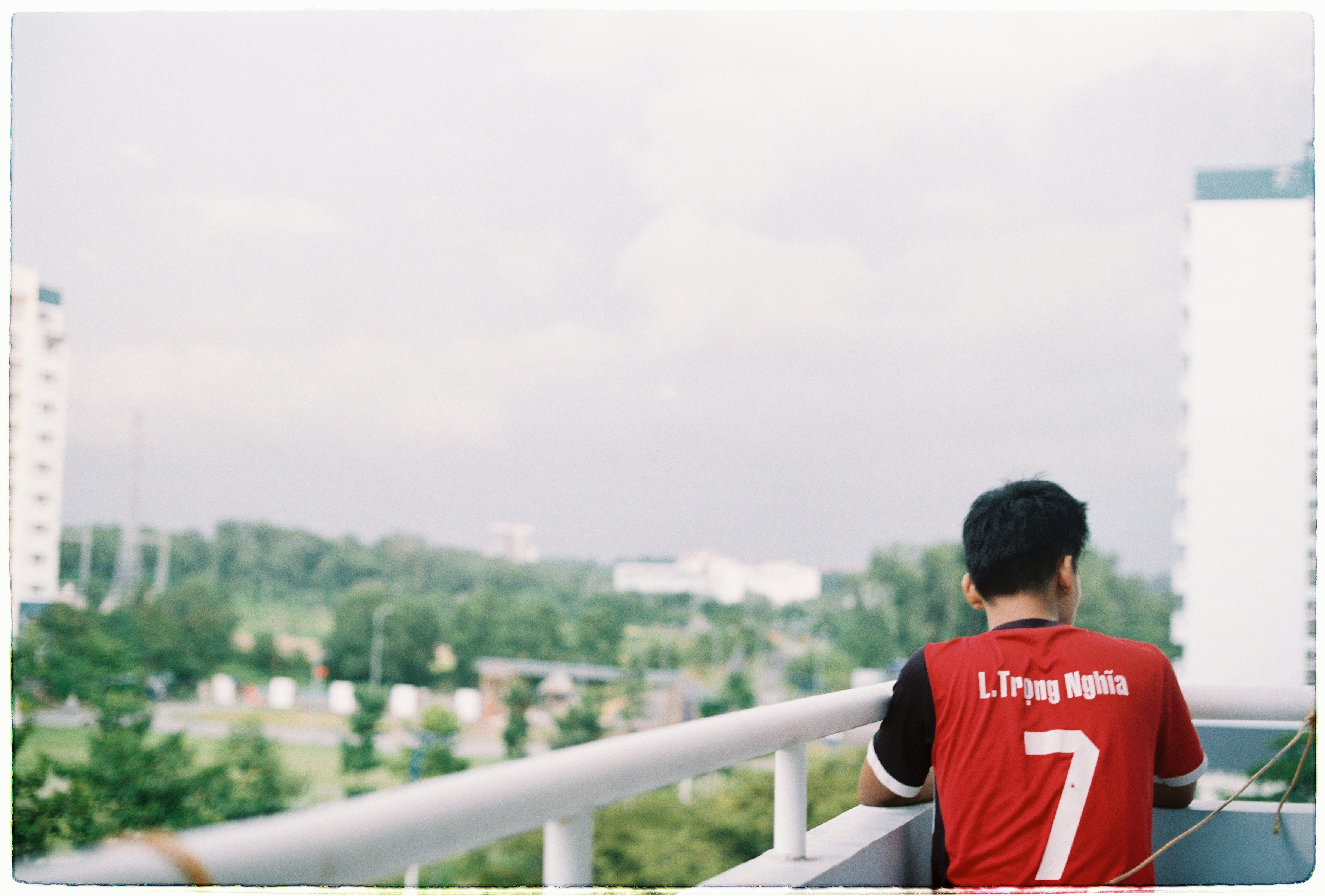 man in red black shirt standing on the corner of the railings