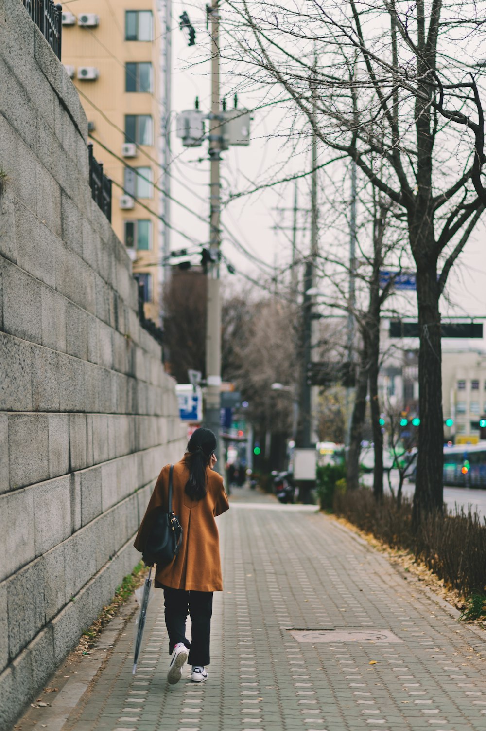 Mujer caminando sola en el camino cerca del edificio