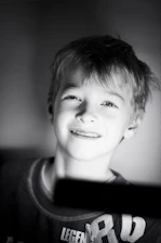 A candid photo of a young Ukrainian child smiling softly while sitting in a sunlit room.