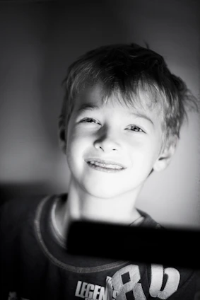 A candid photo of a young Ukrainian child smiling softly while sitting in a sunlit room.