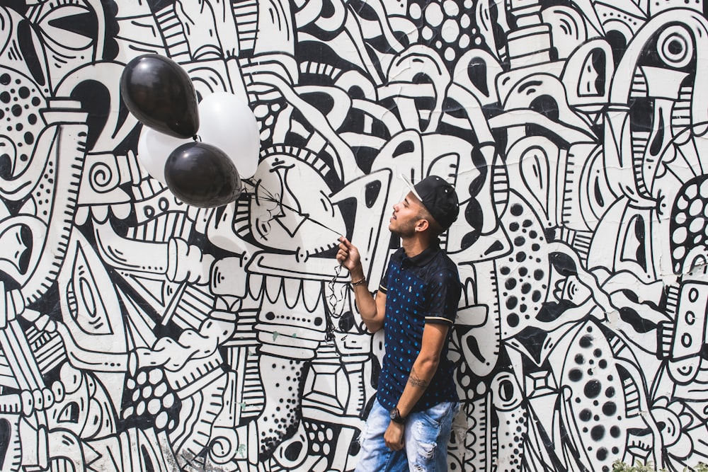 man holding two black balloons