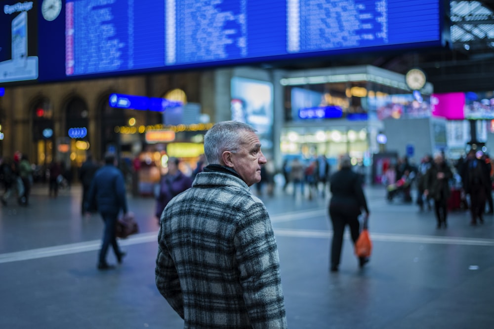 man in green and white plaid coat in busy city street