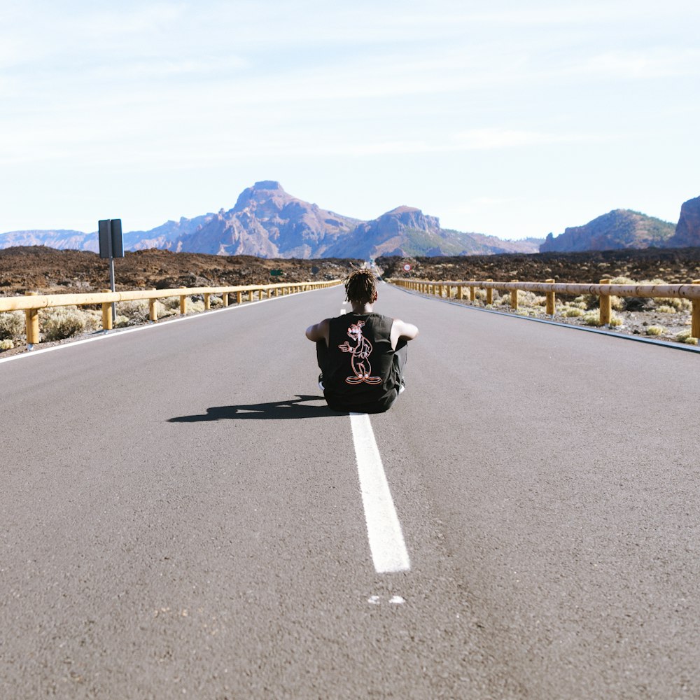 hombre sentado en la carretera