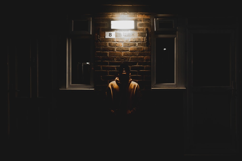 man leaning on wall during nighttime